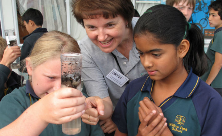 Photo of teacher Sally Smith showing children a water sample.